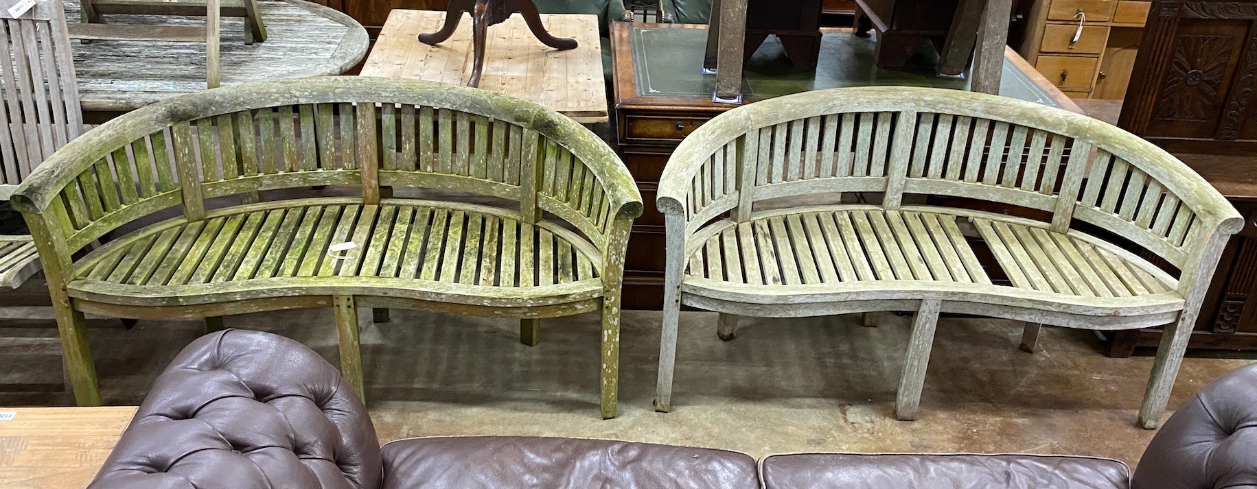 A pair of weathered teak 'banana' garden benches, length 158cm, depth 60cm, height 84cm (one with missing seat slat)